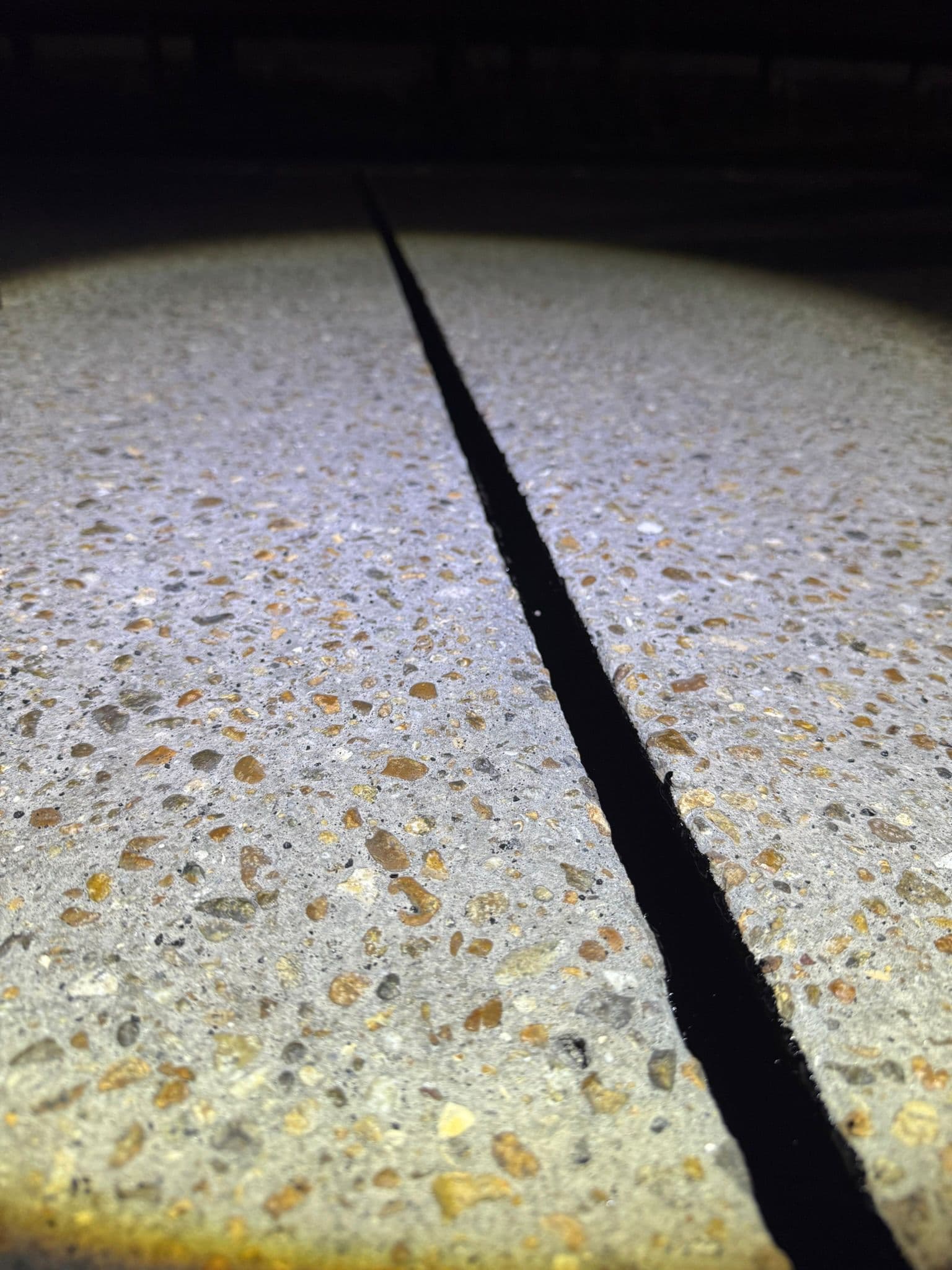 Close-up of a freshly saw-cut groove in an exposed-aggregate concrete surface