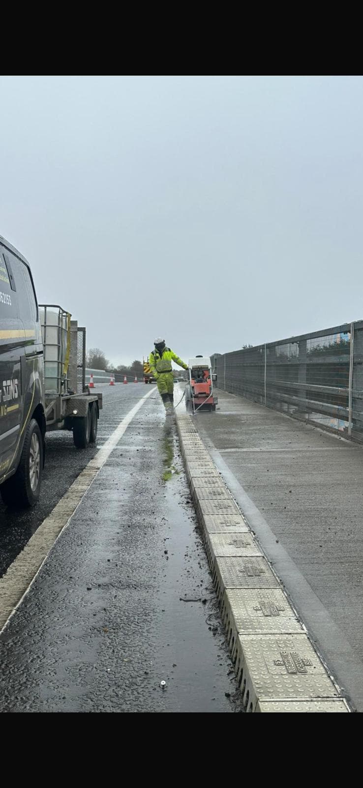 Worker in hi-vis operating a floor saw along a wet concrete surface beside a Shepherd and Sons flatbed van
