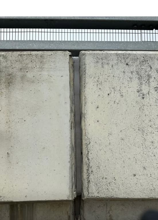 Close-up of a sealed expansion joint between two concrete slabs with a ruler laid across for scale