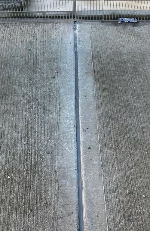 Close-up of a freshly sealed joint running down the centre of a concrete slab surface