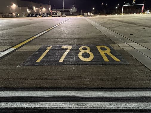 Yellow 178R runway designation marking painted on a tarmac surface