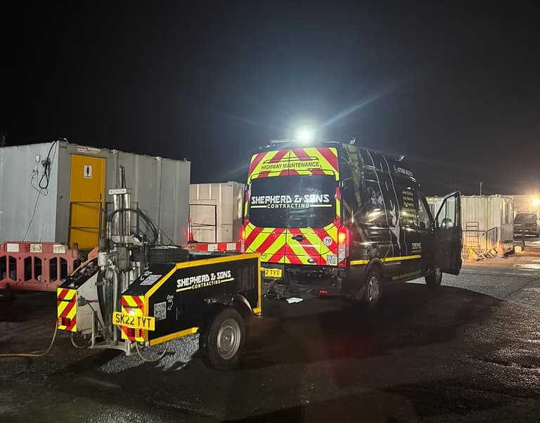 Shepherd and Sons Contracting van and matching trailer with chevron markings parked in a yard at night