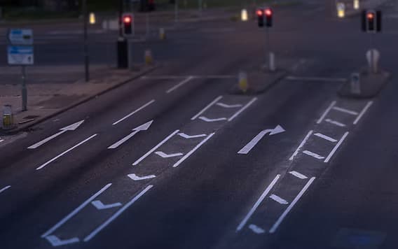 Overhead view of a road with white directional arrow markings and lane lines