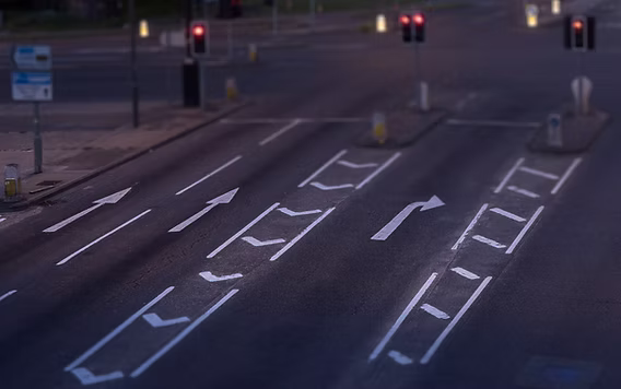 Overhead view of a road with white directional arrow markings and lane lines