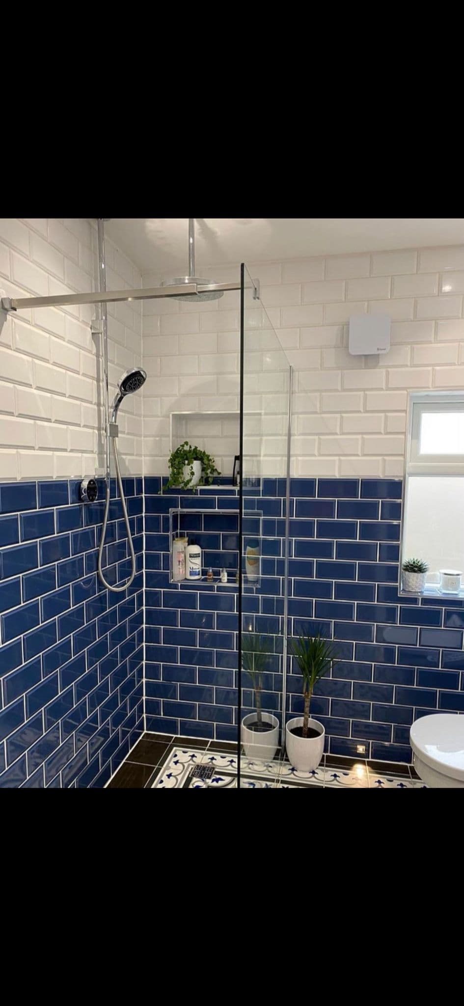 White metro-tiled shower with a blue tile border, glass screen and chrome shower fittings