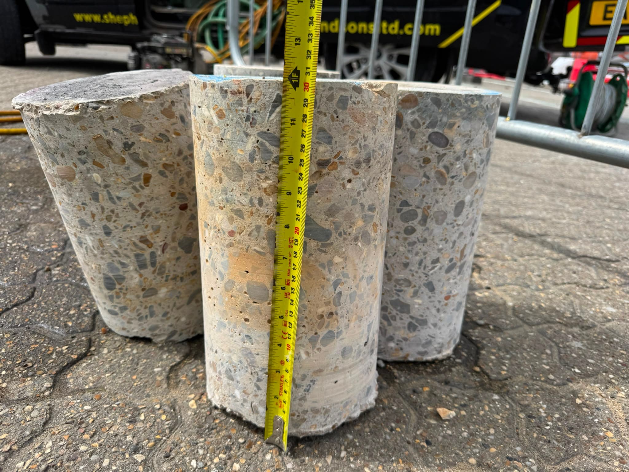 Three concrete cores stood on end beside a tape measure showing their depth