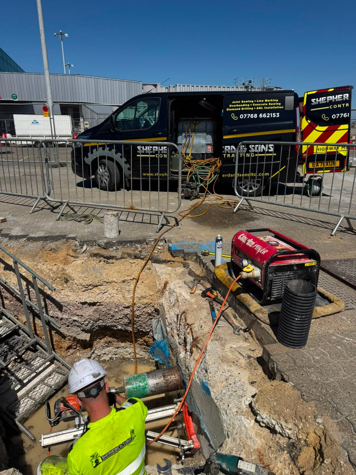 Dark Shepherd and Sons Contracting branded van parked behind metal fencing with hoses and cables on the ground